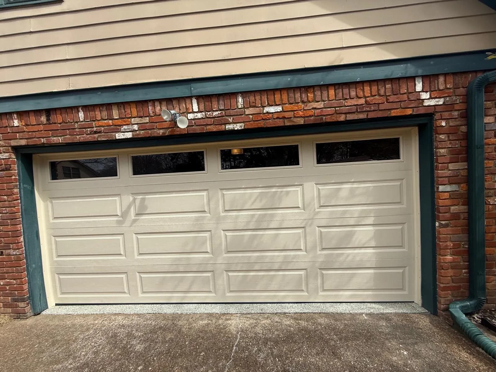 Cream raised-panel garage door with four rectangular top windows