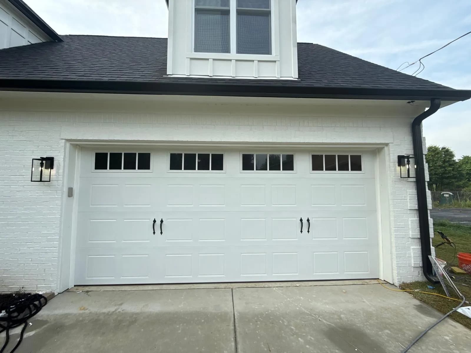 White carriage-style garage door with square top windows and black hardware